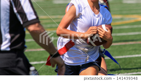 Young Female Athlete Runs With Football During a Flag Football Game Young Female Athlete Runs With Football During a Flag Football Game 141439348