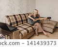 Mature woman playing guitar beside a laptop at home 141439373