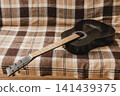 Black acoustic guitar resting on a couch at home 141439375