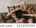 Mature woman practicing guitar with an online lesson 141439384