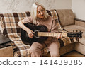 Happy mature woman playing acoustic guitar at home 141439385