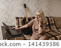 Mature woman talking on a smartphone while using a laptop 141439386