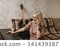 Mature woman working on a laptop during a phone call at home 141439387