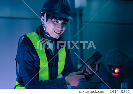 A male worker inspects a rooftop at night using a tablet. Photo courtesy of Denpa Gakuen Educational Foundation, Tokyo Electronics College. A male worker inspects a rooftop at night using a tablet. Photo courtesy of Denpa Gakuen Educational Foundation, Tokyo Electronics College. 141440255