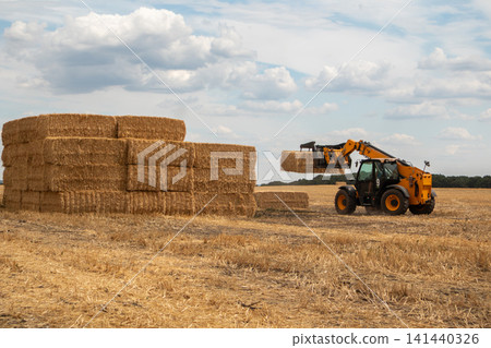 Tractor Moving Hay Bales in Agricultural Field Tractor Moving Hay Bales in Agricultural Field 141440326