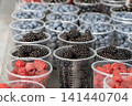 Ripe blackberries and other berries in plastic containers are displayed at a fruit stall in the market. 141440704