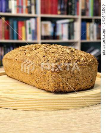 Homemade Keto Seed Bread Loaf Against Bookshelf Background Homemade Keto Seed Bread Loaf Against Bookshelf Background 141441069