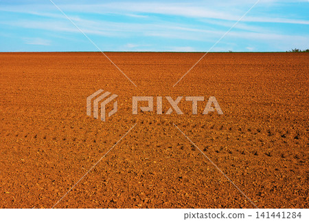 Freshly plowed agricultural field under a lightly clouded sky in the spring time Freshly plowed agricultural field under a lightly clouded sky in the spring time 141441284