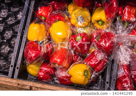 Amsterdam, Netherlands, January 25th 2025. Mixed bell peppers in plastic crate at grocery store. Colorful red and yellow bell peppers wrapped in plastic film and displayed for sale. Amsterdam, Netherlands, January 25th 2025. Mixed bell peppers in plastic crate at grocery store. Colorful red and yellow bell peppers wrapped in plastic film and displayed for sale. 141441295