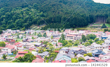 A peaceful mountain village and townscape surrounded by lush green mountains. A peaceful mountain village and townscape surrounded by lush green mountains. 141441529