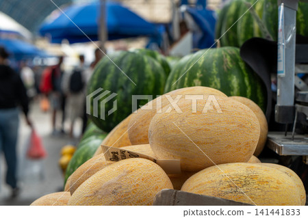 Ripe and juicy melons lie on the counter in the market or bazaar. Sale of ripe and fresh vegetables and fruits at the farmers' market. Close-up. Ripe and juicy melons lie on the counter in the market or bazaar. Sale of ripe and fresh vegetables and fruits at the farmers' market. Close-up. 141441833