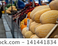 Ripe and juicy melons lie on the counter in the market or bazaar. Sale of ripe and fresh vegetables and fruits at the farmers' market. Close-up. 141441834