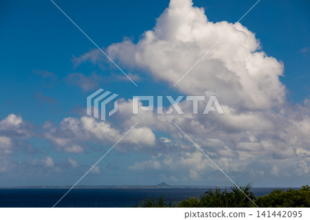 A view of Iejima and Shiroyama Island from the sea off Okinawa, showcasing the magnificent cumulonimbus clouds in summer. 141442095