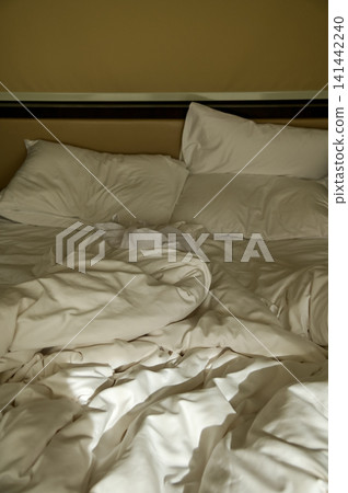 Close-up of the bed with white sheet in the room. Hotel or apartment scene. Close-up of the bed with white sheet in the room. Hotel or apartment scene. 141442240