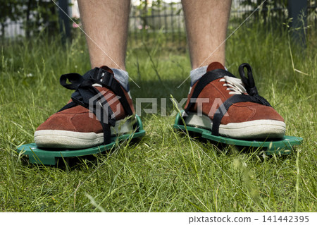 Lawn aerator shoes on grass, illustrating practical garden maintenance for healthy turf and simple manual soil care in home yards. 141442395