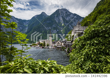 Hallstatt village with its church on the lake in the Austrian Alps, illustrating scenic tourism in Europe and alpine travel charm. Hallstatt village with its church on the lake in the Austrian Alps, illustrating scenic tourism in Europe and alpine travel charm. 141442396