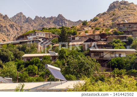 Rural village with solar panel, surrounded by rugged hills and vegetation Rural village with solar panel, surrounded by rugged hills and vegetation 141442502