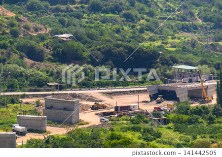 Construction site on hillside with heavy machinery 141442505