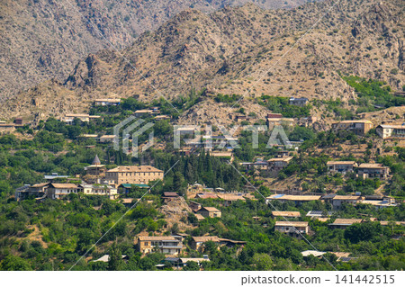 Village perched on hillside with stone houses, greenery Village perched on hillside with stone houses, greenery 141442515