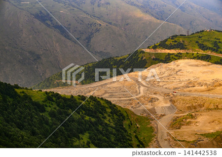Winding road crosses a mountain valley Winding road crosses a mountain valley 141442538