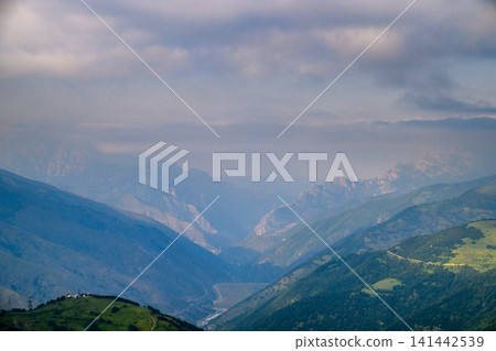 Landscape photo with mountain valley, clouds, and green slopes Landscape photo with mountain valley, clouds, and green slopes 141442539