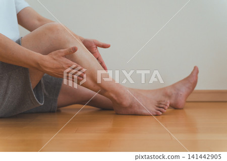 畫面中,一名四十多歲的男子坐在地板上,為自己按摩小腿。 畫面中,一名四十多歲的男子坐在地板上,為自己按摩小腿。 141442905
