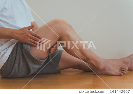 畫面中,一名四十多歲的男子坐在地板上,為自己按摩大腿。 畫面中,一名四十多歲的男子坐在地板上,為自己按摩大腿。 141442907