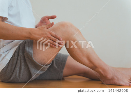 畫面中,一名四十多歲的男子坐在地板上,為自己按摩大腿。 畫面中,一名四十多歲的男子坐在地板上,為自己按摩大腿。 141442908