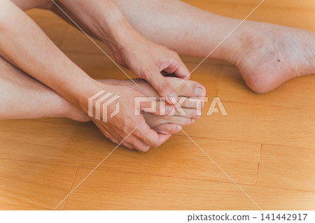 A scene of a man in his 40s sitting on the floor and massaging his toes. A scene of a man in his 40s sitting on the floor and massaging his toes. 141442917