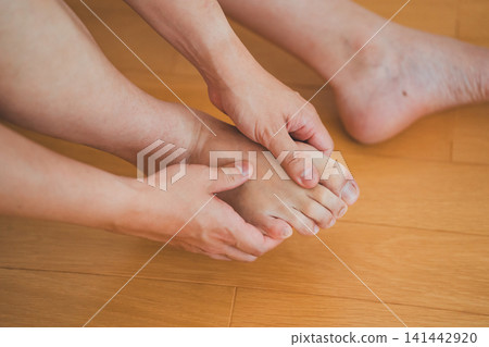 畫面中,一位四十多歲的男子坐在地板上,雙手按摩自己的腳趾。 畫面中,一位四十多歲的男子坐在地板上,雙手按摩自己的腳趾。 141442920