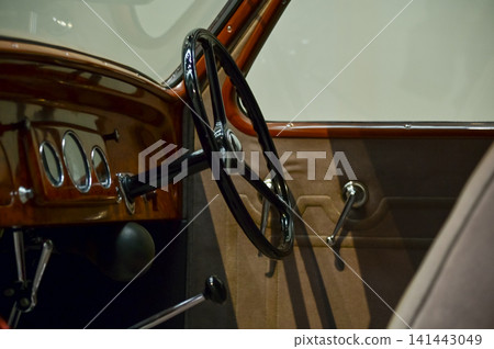 Detail of the interior of a vintage car. Retro car. Close-up of the old steering wheel, console, seats, insides of the retro car. Interior of a classic vintage car Detail of the interior of a vintage car. Retro car. Close-up of the old steering wheel, console, seats, insides of the retro car. Interior of a classic vintage car 141443049