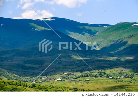Panoramic view of a peaceful valley surrounded by mountain ranges with lingering Panoramic view of a peaceful valley surrounded by mountain ranges with lingering 141443230