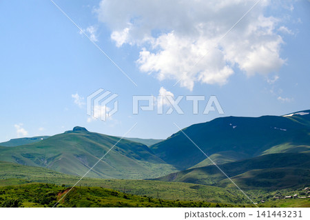 Rolling green hills with valley and distant ridge Rolling green hills with valley and distant ridge 141443231