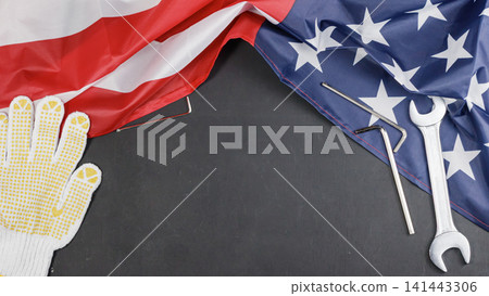 Patriotic American flag with spanner wrench, hex key, and work glove on dark background with copy space in the center. High Quality Photo 141443306