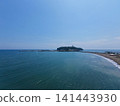 A photo taken from a high vantage point at Katase Higashihama Beach, showing Enoshima Island surrounded by the sea and the sandy beach. 141443930