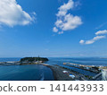 A photo taken from a high vantage point at Katase Higashihama Beach, showing Enoshima Island surrounded by the sea and the sandy beach. 141443933
