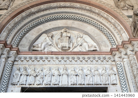 The central portal of the Cathedral of St Martin in Lucca. Lunette depicts the Redeemer in a mandorla held by two angels and Virgin Mary with Apostles, Lucca, Italy. The central portal of the Cathedral of St Martin in Lucca. Lunette depicts the Redeemer in a mandorla held by two angels and Virgin Mary with Apostles, Lucca, Italy. 141443960