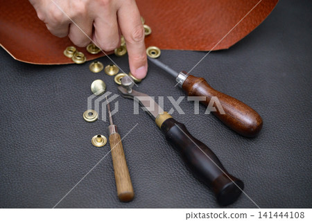 The hands that attach snaps in leather crafting 141444108