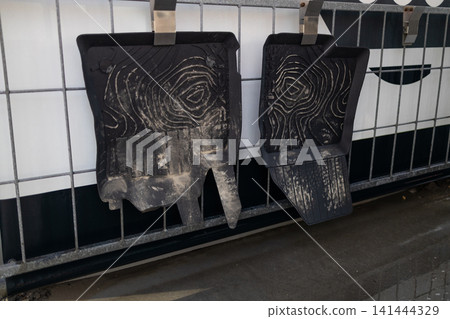 Dirty rubber car mats hanging on clips at self-service car wash station. Dirty rubber car mats hanging on clips at self-service car wash station. 141444329