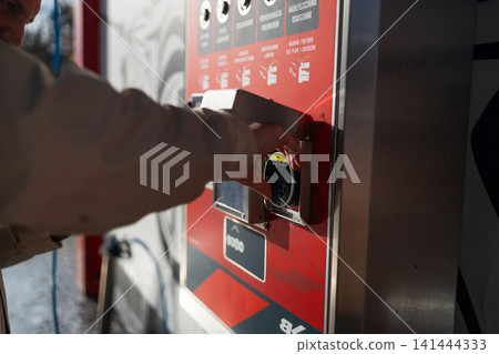 Hand pressing button on automated vending machine at manual carwash station. Hand pressing button on automated vending machine at manual carwash station. 141444333