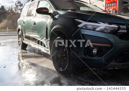 New dark khaki utility vehicle on wet asphalt after washing at manual carwash. New dark khaki utility vehicle on wet asphalt after washing at manual carwash. 141444335