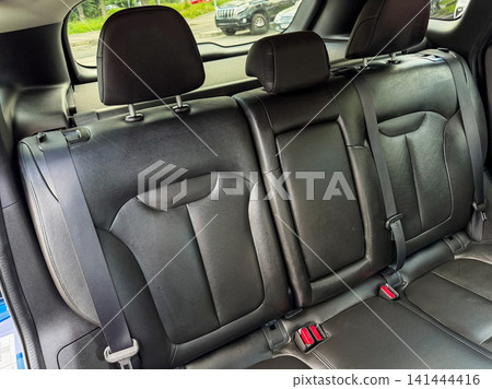 View of the back seat of a car showing the seat design and seat belts with a blurred background of another vehicle View of the back seat of a car showing the seat design and seat belts with a blurred background of another vehicle 141444416
