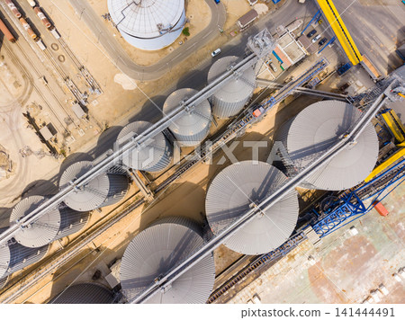 Overview of large industrial silos and equipment in an agricultural processing facility near a city Overview of large industrial silos and equipment in an agricultural processing facility near a city 141444491