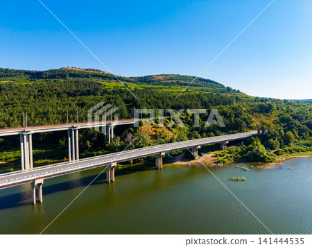 Views of a bridge over water with green hills in the background during clear weather in a rural area Views of a bridge over water with green hills in the background during clear weather in a rural area 141444535