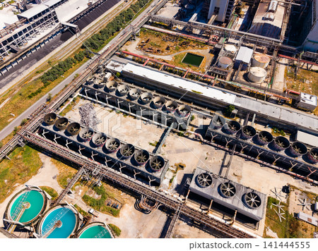 View of an industrial area showing cooling towers and machinery near a plant during daytime in an urban setting 141444555