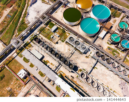 Industrial facility with storage tanks and cooling systems located in a large open area during daytime Industrial facility with storage tanks and cooling systems located in a large open area during daytime 141444643