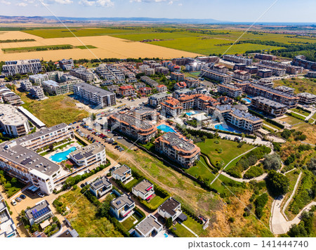 Aerial view of a residential area with houses, pools, and green fields in the background during daytime Aerial view of a residential area with houses, pools, and green fields in the background during daytime 141444740