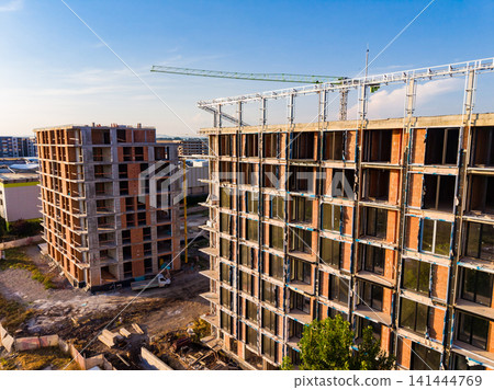 Building construction site with cranes and new structures in progress during daylight Building construction site with cranes and new structures in progress during daylight 141444769