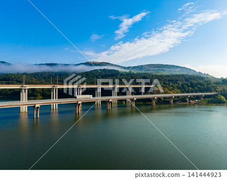 Bridge spans over water with green hills and blue sky in the background during daytime Bridge spans over water with green hills and blue sky in the background during daytime 141444923