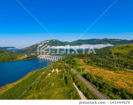 Scenic view of a bridge over water with hills and clear sky in the background during daytime 141444929
